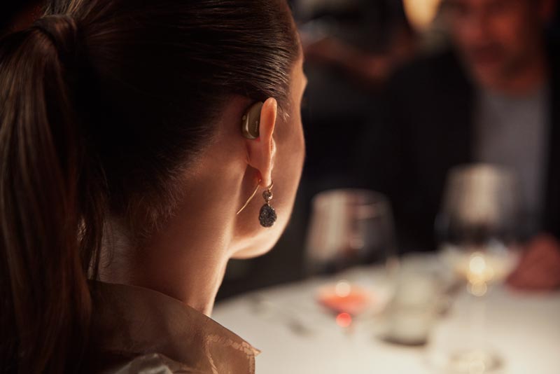 Woman wearing Widex Moment hearing aid back view